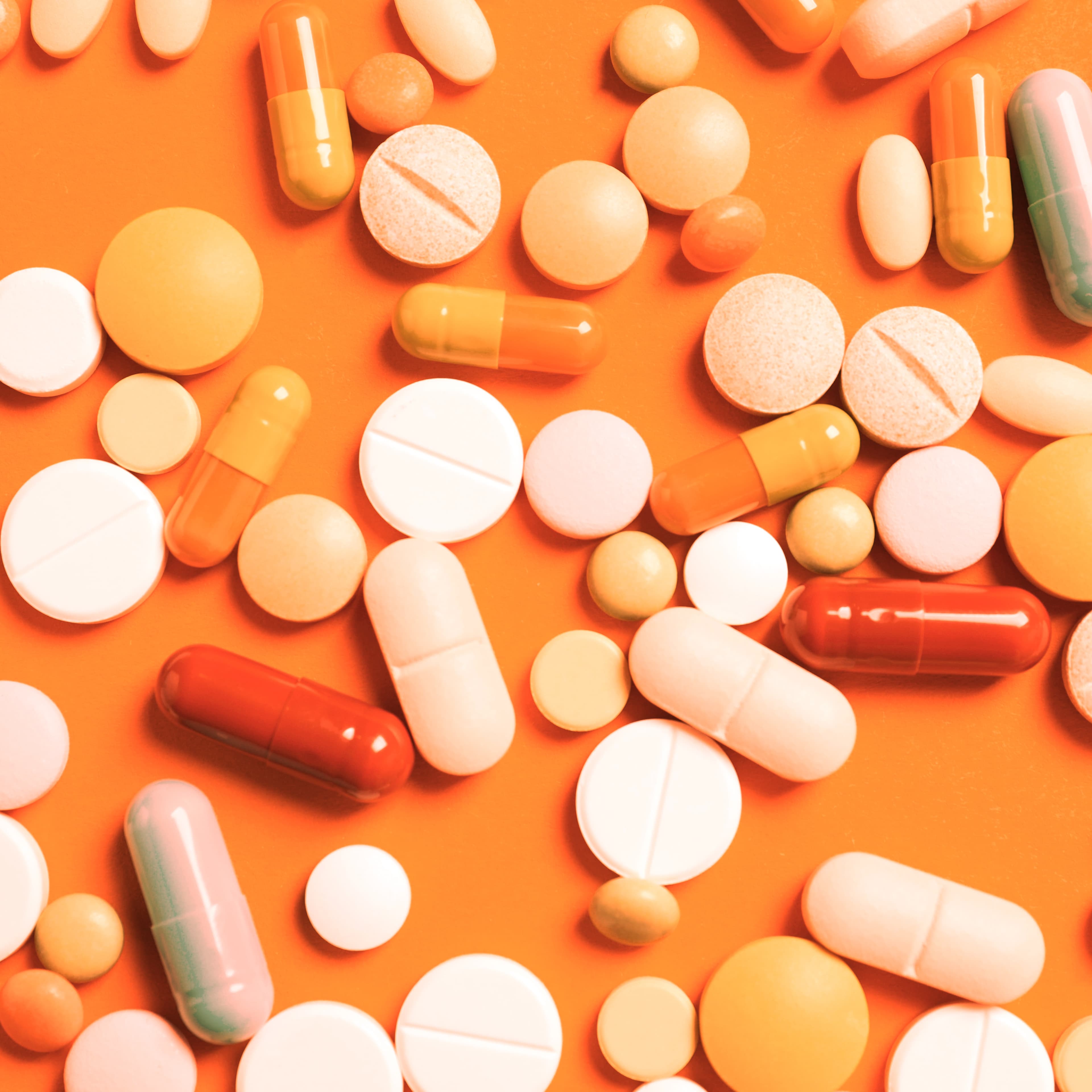 scattered pills of different sizes on orange